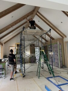 Craftsmen are fabricating white oak collar tie beams in an interior space of this new home being built by Joseph Philip Craig Custom Homes